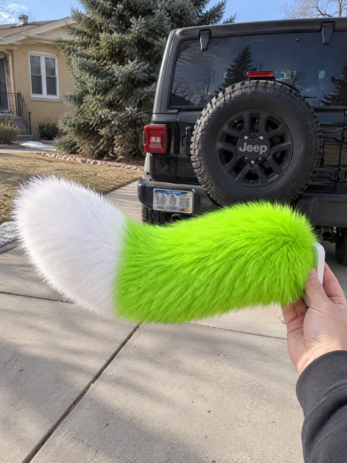 Neon Green & White | Wagride tail held in a hand in a parking lot